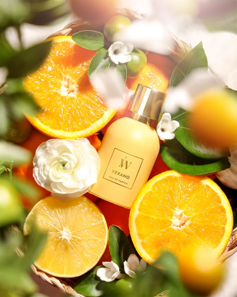 Ida Warg gul parfymflaska med svävande citroner och apelsiner. En energisk och fräsch komposition med fokus på citrusnoter och färgstarkt content marketing, perfekt för en kosmetik-portfolio.