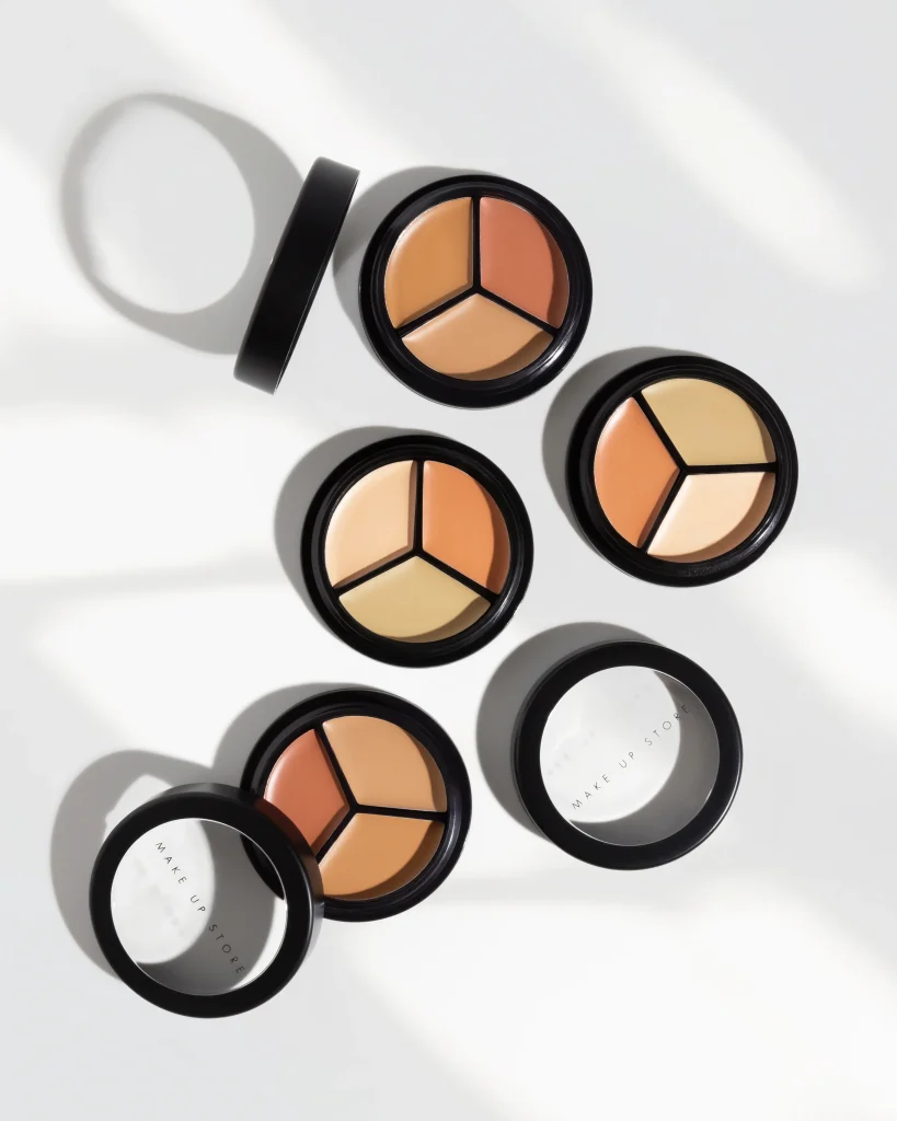 Professionell flatlay-fotografering av Make Up Store Cover All Mix concealer. Bilden visar fyra öppna dosor med olika nyanser arrangerade med grafiska skuggor på en vit yta.