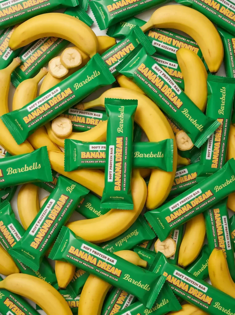 AI-genererad produktbild på en Barebells Banana Dream proteinbar med en bananer, perfekt för hälsomarknadsföring och e-handel av Sköneskog Studio.
