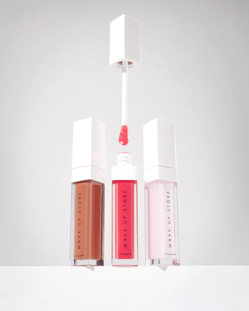 Studiofotografering av Make Up Store Lip Plumper med fokus på textur och färg. Symmetrisk komposition på vit bakgrund som visar produktens glans och förpackningsdesign. Högkvalitativt content för skönhetsbranschen och e-handel.